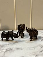 Front view of three hand carved wooden African animal figurines: elephant, rhinoceros, hippopotamus