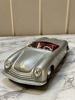 Front three-quarter view of the silver 1948 Porsche 356 Roadster diecast model showing car body and red interior.