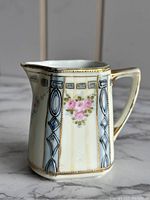 Side angle of Nippon 1940s creamer showing pink rose floral pattern and blue vertical stripe design with gold gilt border.