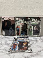 Four Star Wars comics displayed upright in plastic sleeves, showing front covers with Darth Vader and Star Wars action figure cardback designs.