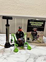Vintage Space Pets High-Hopping Moonworm mechanical frog-like toy with black round body and green articulated legs, manual pump, and original box.