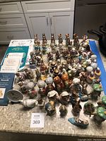 Overview of countertop display showing approximately 40 porcelain figurines, stack of four books and one plate