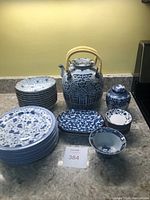 Photo showing the collection on countertop including plates, teapots, canisters, bowls, and trays in blue and white patterns.