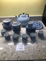 Full set displayed on counter including teapot, cups, saucers, and trivets