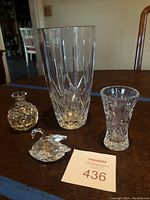 Photo shows three crystal vases and one Swarovski swan figurine on brown table