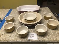 Full set of Emile Henry ceramic bakeware items on countertop including casserole dish, pie plates, and six bowls arranged in a circle.