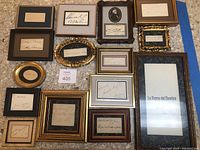 Full view of 14 different framed autographs in varied frames including ornate gold, black and wood