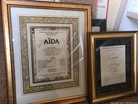 Two framed Opera Company of Boston programs: Aida and La Bohème, both autographed in gold frames.