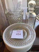 Clear hobnail glass pitcher and stack of hobnail plates with MaxSold label