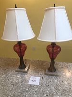 Pair of two electric table lamps with cream shades, placed on a marble countertop against a yellow wall.