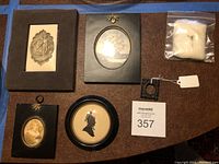 Overview of antique miniatures collection including carved notebook, framed prints, silhouettes and pin.
