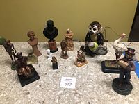 Overview photo showing all figurines on countertop including monkeys, busts, white bird with red beak, and figures playing accordion.