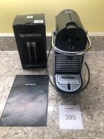 Front view of Pixie espresso machine on countertop with Aeroccino 3 box, instruction manual and lot number card.