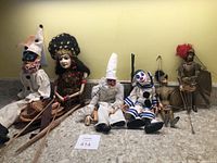Front view of 6 puppets arranged sitting, showing detailed costumes and facial features.