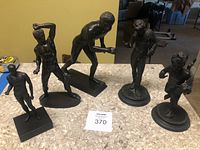 Group photo of five Grecian athlete statues on counter displaying differences in size and pose.