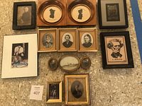 Full overview of the 13 framed portraits, silhouette images, and photographs arranged on a surface showing variety of frame shapes and styles.