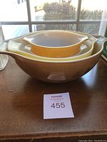 Stacked vintage Pyrex mixing bowls in brown, yellow and white with floral patterns seen from above and side.