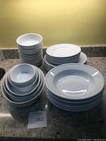 View of all dishes stacked by type, showing bowls and plates in white ceramic.