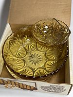 Open box showing the amber chip and dip set with pressed glass starburst patterns, including larger chip bowl, smaller dip bowl, and brass plated holder.