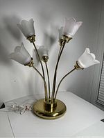 Full view of the vintage brass table lamp with five flower-shaped frosted glass shades on brass stems and round base.