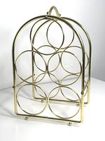 Full view of the vintage brass wine rack showing the arched frame and circular drink holders.