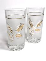 Two vintage Libbey glass tumblers side by side showing etched wheat design with gold accents