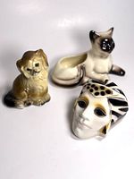 Photo showing chalkware dog figurine, ceramic cat planter, and a ceramic mask on a white background