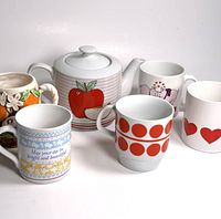 Lot of 5 mugs and 1 apple design teapot displayed against a white background showing various mug designs and teapot artwork