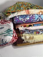 Stack of assorted vintage linens showing various colorful patterns including floral, handprints, and Disney characters.