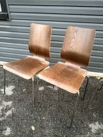 Two Ikea Gilbert chairs with bent plywood seats and backs, metal legs, showing wood grain and minor wear