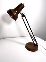 Full view of the brown vintage adjustable table lamp with conical shade and arm extended.