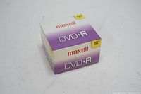 Sealed box of 50 Maxell DVD+R blank recordable DVDs photographed from an angle showing branding and quantity.