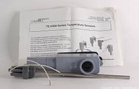 Photo showing the Johnson Controls temperature sensor with probe and polycarbonate enclosure along with user manual.