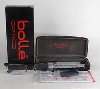 Photo of eyeglasses with Bolle branded box, hard case, cleaning cloth, and instruction manual.