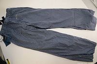 Pair of pajama pants laid flat on white surface, showing their full length and stripe pattern