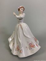 Side view photo of the Royal Doulton porcelain figurine showing detailed floral decorations on the flowing dress and bonnet with rose decoration.