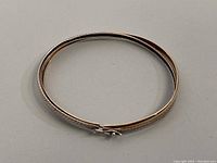 Top view of the hinged bangle showing the mixed silver and gold finish with textured design.