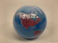 Front view showing North and South America continents on the blown glass globe with blue ocean.