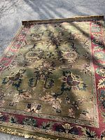 Full view of the large Afghan wool rug showing overall design, colors, and condition under daylight.