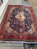 Full view of rug laid out on pavement showing overall pattern and fringe ends