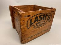 Angled front-side view of wooden crate showing Lash's Quality Products branding and cutout handle.