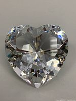 Front angled view of the clear heart-shaped crystal paperweight showing its geometric cuts that reflect light.