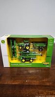 Front view of the John Deere Harvesting Set box showing tractor, combine harvester, grain cart, and header attachment in clear plastic packaging