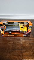 Full side view of the NewRay Long Haul Trucker die-cast model in original packaging showing yellow cab and flatbed trailer.