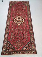 Full view of red runner rug with central medallion and floral border on a neutral floor