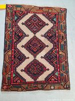 Full view of hand-knotted wool Persian rug with triple medallion pattern and tribal border motifs in beige, red, green, orange, and black.