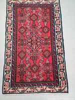 Full top view of red wool Persian rug with tribal mahi motif and cream border.