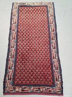 Full view of the hand knotted wool Persian rug with red and cream paisley design and border, showing overall pattern and condition.