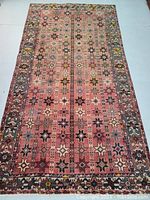 Full view of hand-knotted wool rug with repeating star pattern and floral borders.