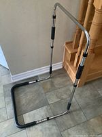 Full view of the adjustable bed safety rail showing the metal frame and padded handles.